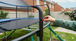 A close-up photorealistic illustration of the internal engineering of a 6ft trampoline, focusing on the high-tension galvanised steel springs connecting the mat to the frame, and secure pole joints.