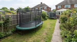 Best oval trampoline options positioned alongside a fence line in a narrow suburban garden in the UK.