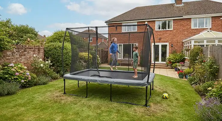 A children's rectangular trampoline installed in a typical British back garden with a lawn. best rectangular trampoline