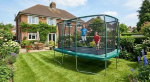 Children having fun bouncing on a large garden trampoline with a safety enclosure.